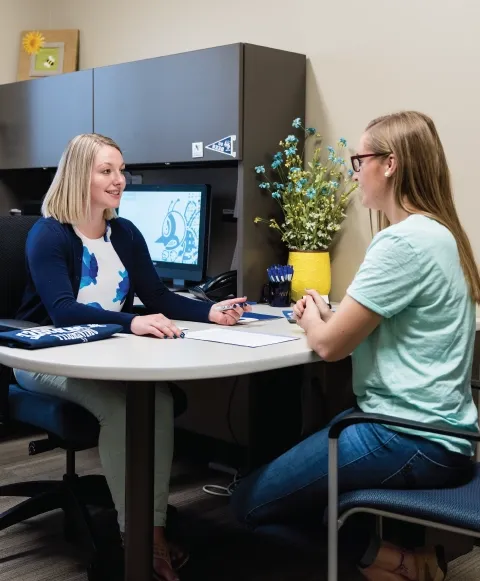 Admissions counselor at a desking helping a student.